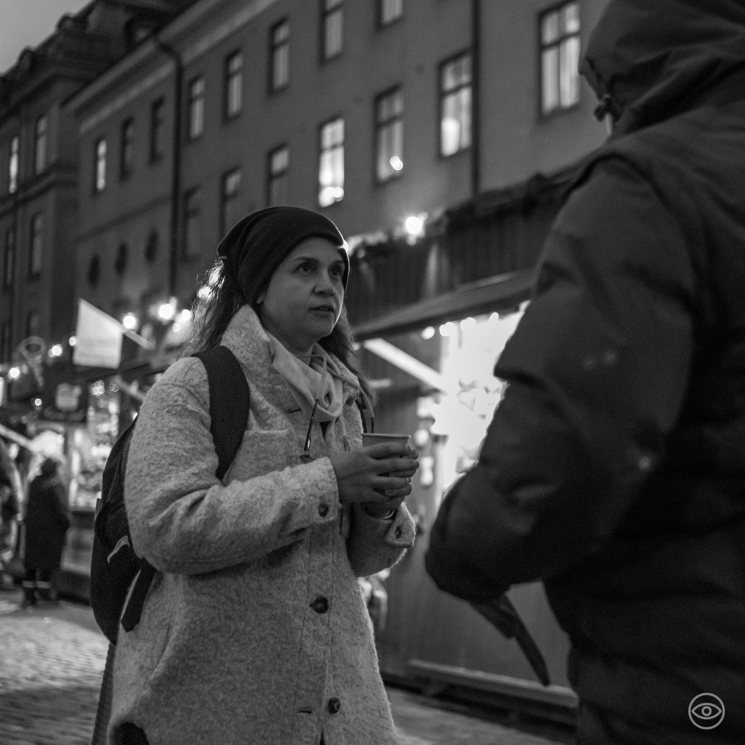 Woman holding a warm drink at a winter Christmas market in black and white street photography.