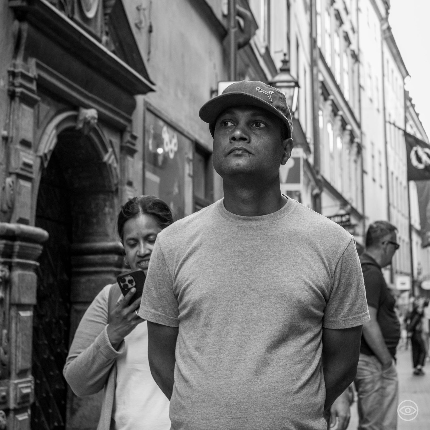 Young man in a cap looking upward on a historic city street, black and white street photography.