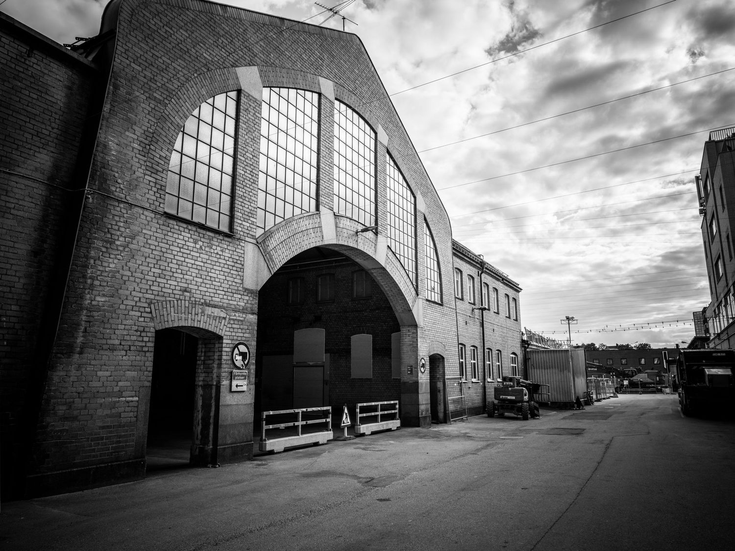 Exterior corner view of an abandoned brick industrial building with arched window facade.