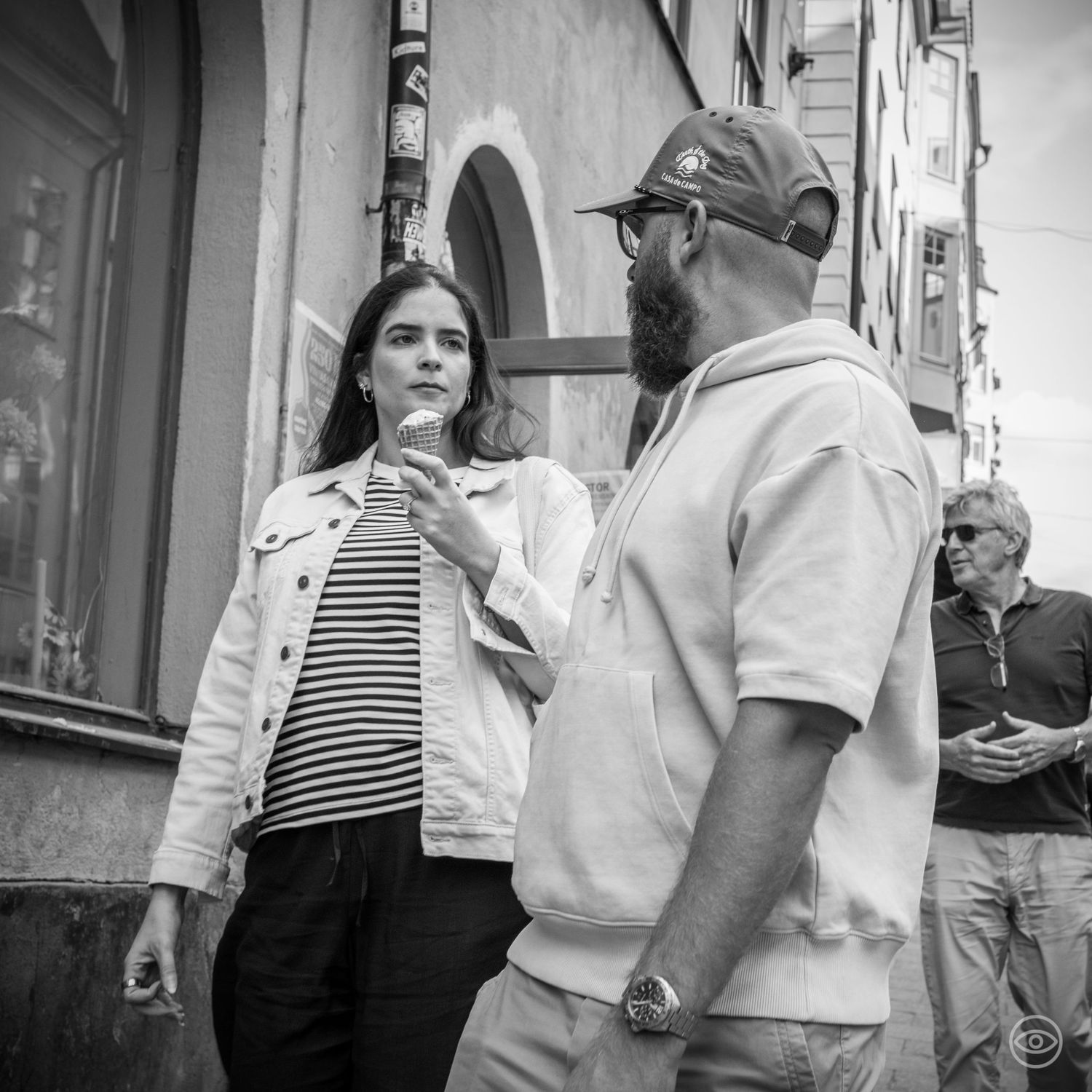 Bearded man and dark-haired woman in conversation on a city street, black and white street photo.