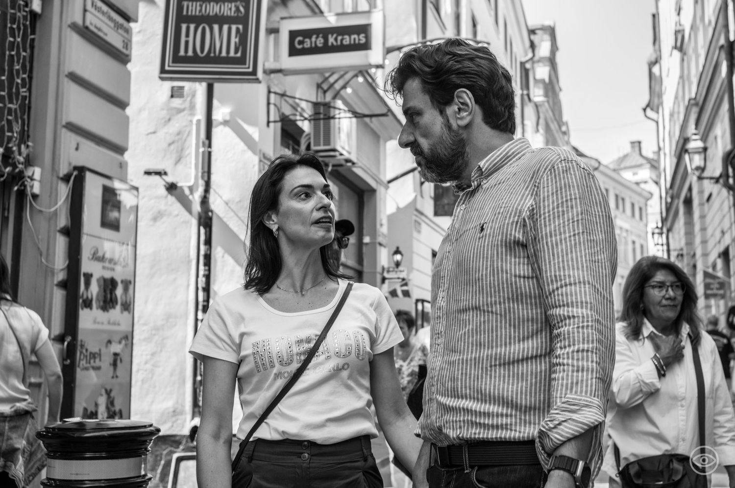 Man and woman share an intense conversation on a busy European shopping street in black and white.