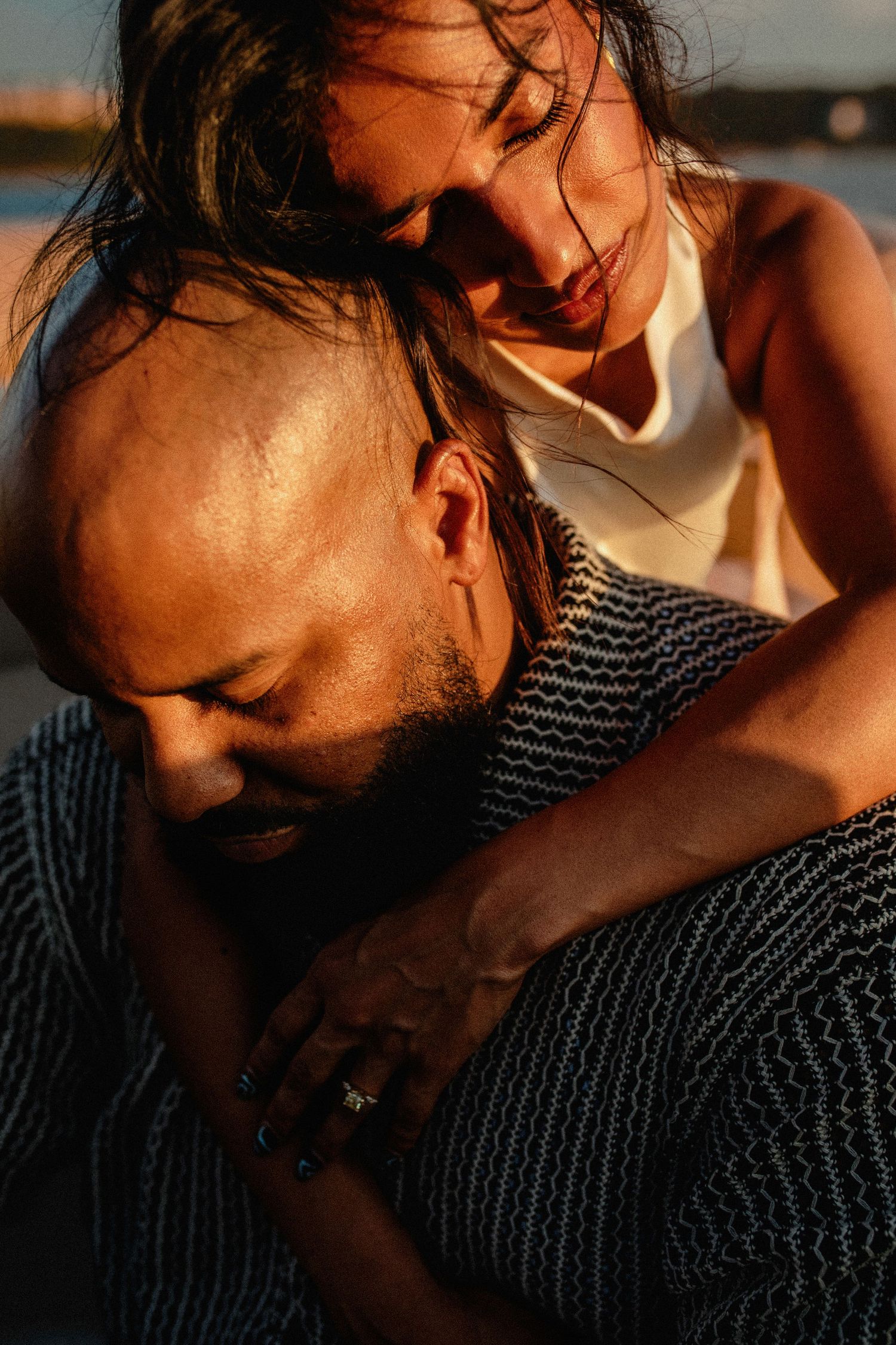 Intimate golden hour portrait of couple embracing on a boat near the water.