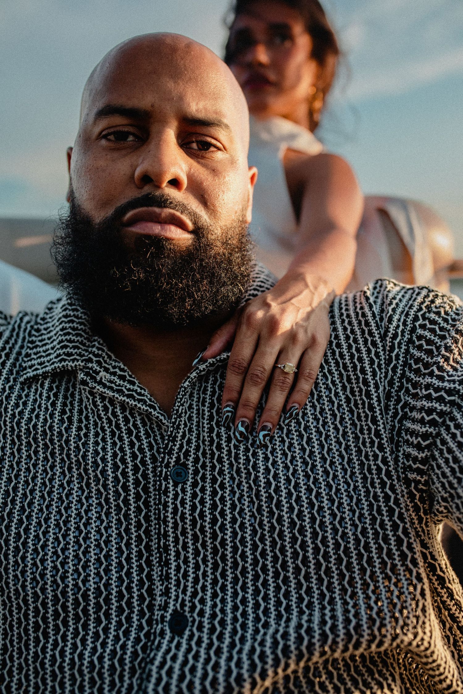 Close-up portrait of bearded bald man with woman resting hand on his shoulder on a boat.