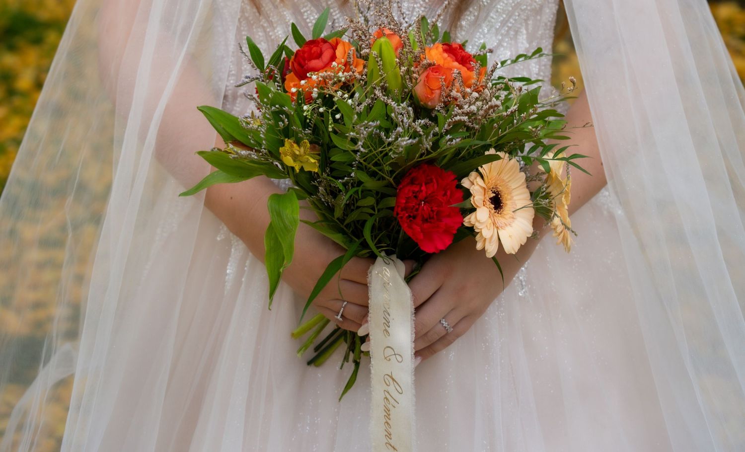 Photo d'un bouquet de mariée aux fleurs orange et jaunes dans les mains de la mariée — photographe mariage Lorraine