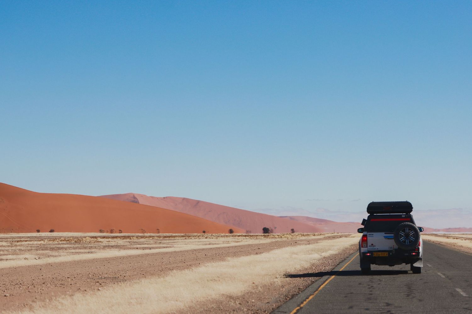 4x4 à toit-tente sur la route du désert face aux dunes — road trip en Namibie