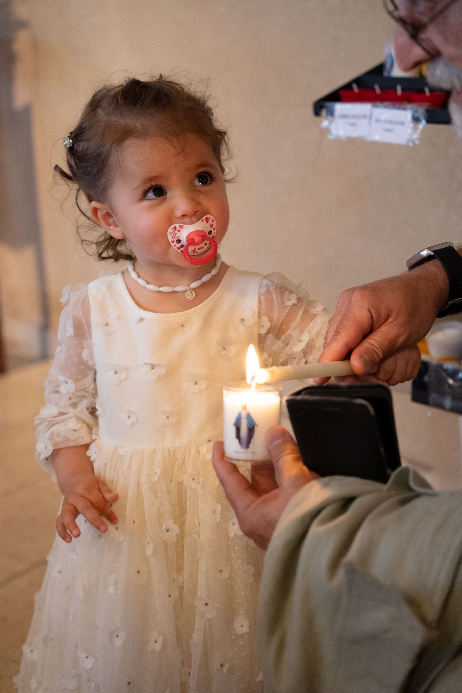 Enfant en robe de cérémonie tenant un cierge allumé — photographe baptême Lorraine