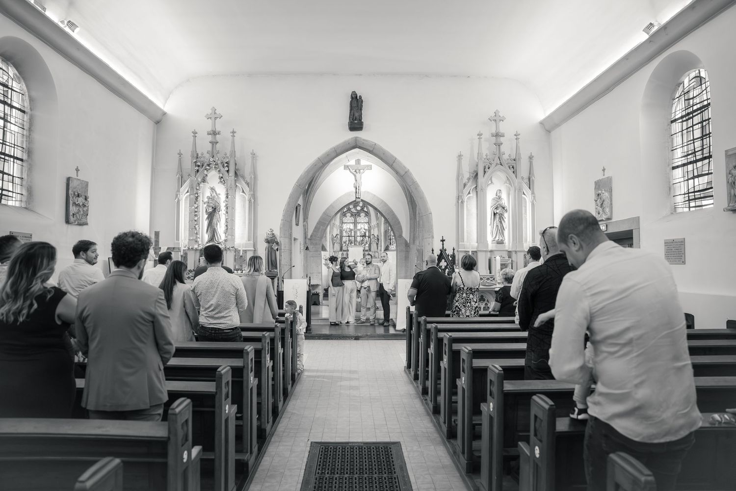 Assemblée recueillie dans la nef pendant la célébration, photographie noir et blanc — photographe baptême Lorraine