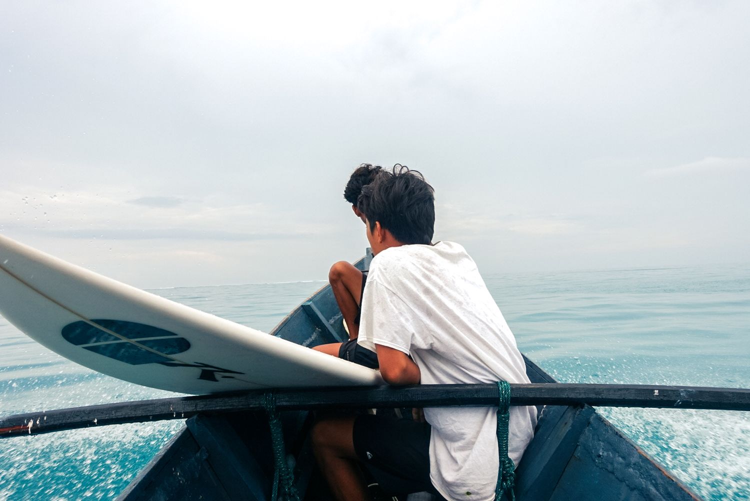 Surfeur à l'avant d'un bateau, planche sous le bras, vers le spot — îles Mentawaï, Indonésie