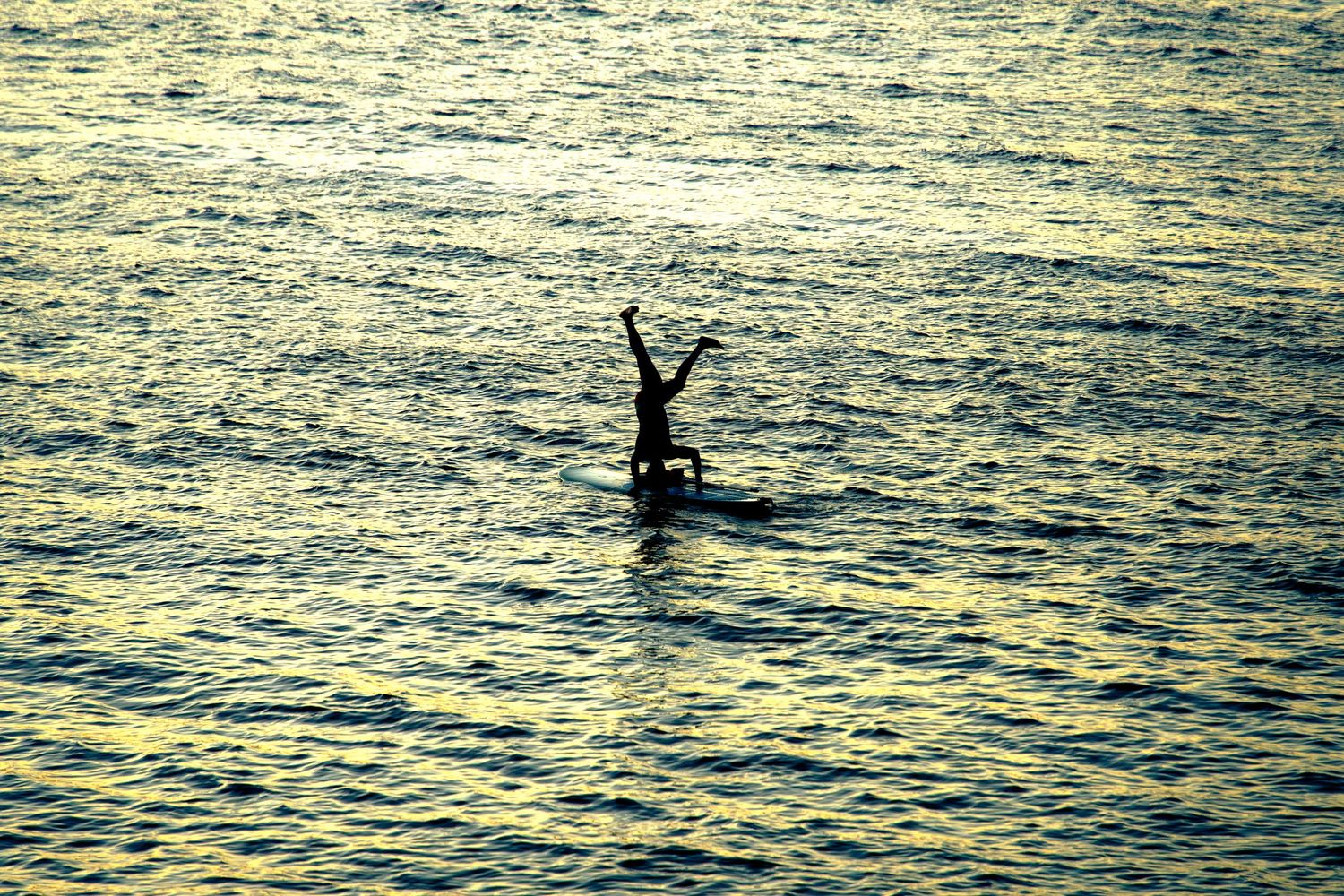 Photo d'un surfeur en contre-jour levant les bras sur sa planche — Itacaré, Bahia