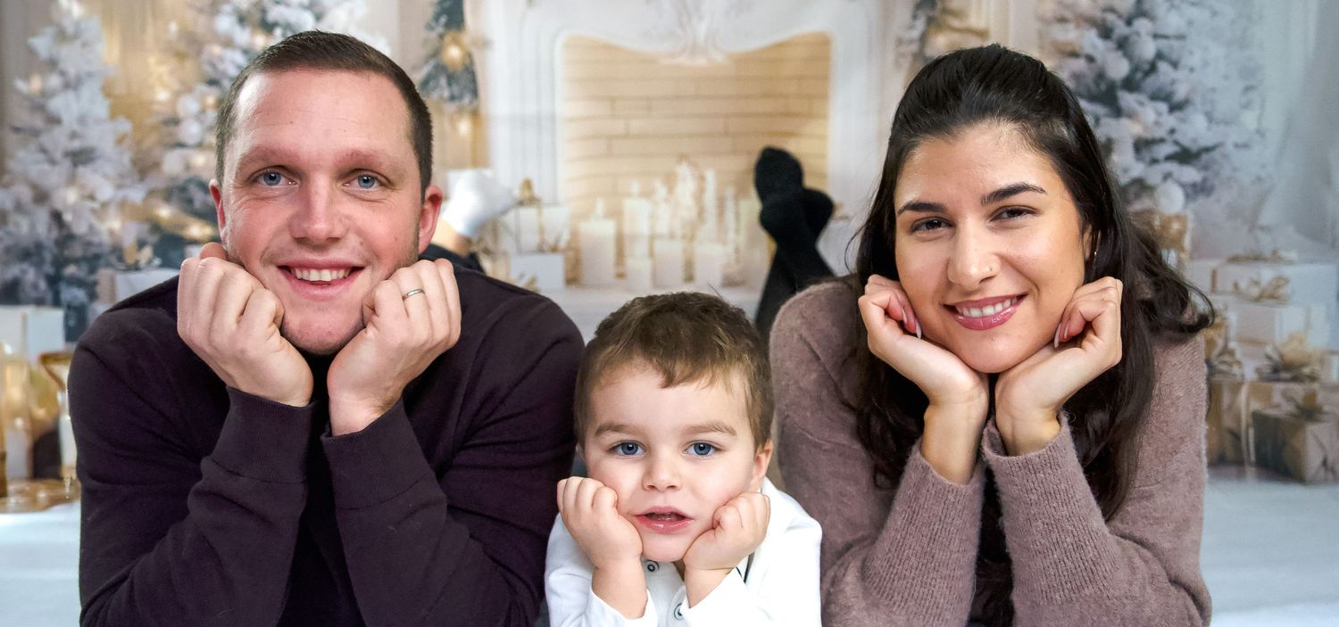 Portrait de famille en studio, parents et petit garçon la tête dans les mains, décor de Noël – séance photo famille