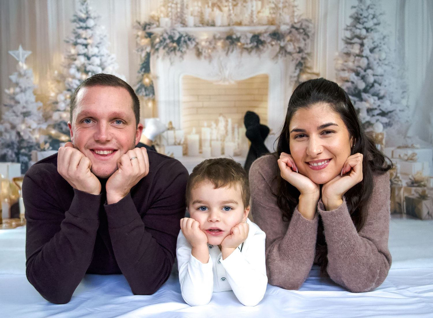 Photo lifestyle de famille en studio — parents et jeune enfant dans un décor de Noël en studio