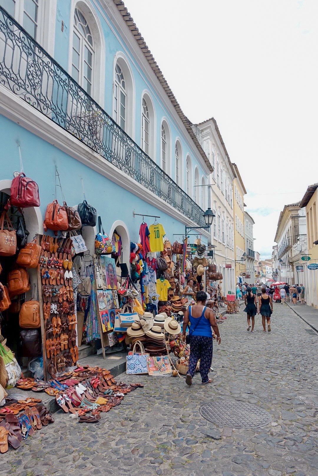 Reportage photo Bahia - Étal d'artisanat coloré devant une façade coloniale du Pelourinho, Salvador de Bahia
