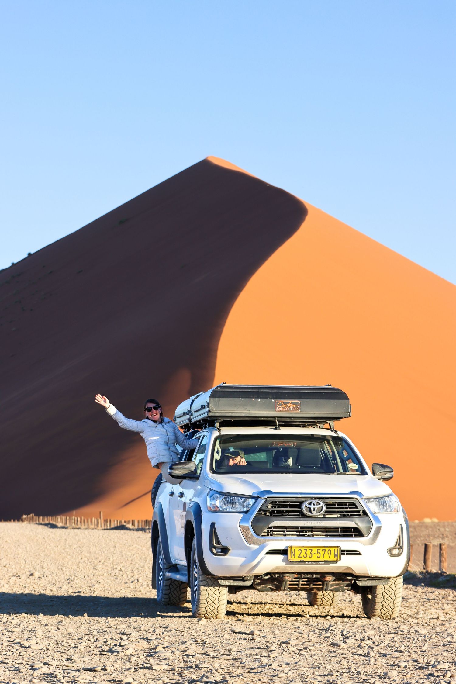 Voyageuse bras levés devant une dune de Sossusvlei, 4x4 à toit-tente — road trip en Namibie