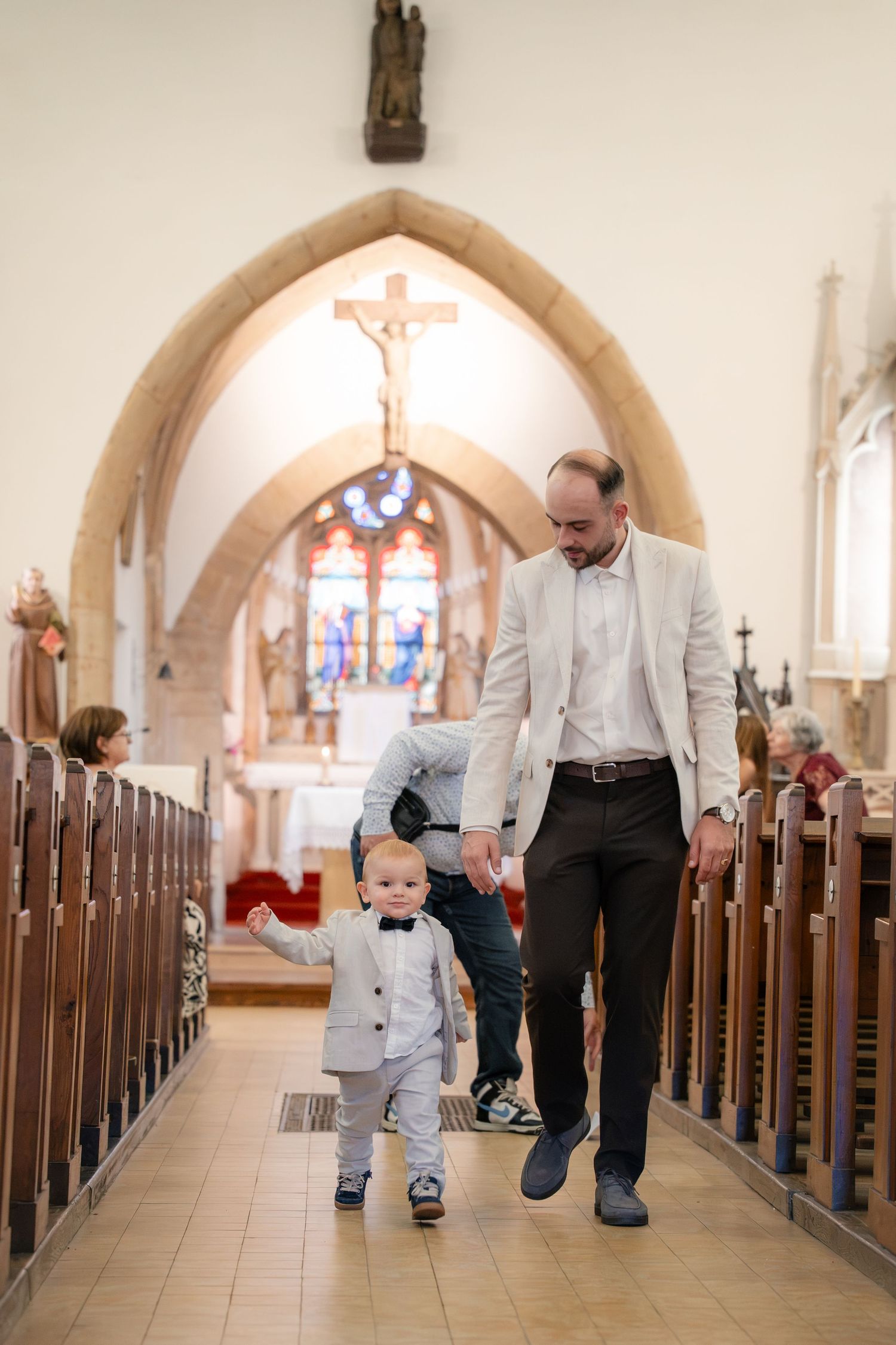 Père et enfant main dans la main dans l'allée centrale — photographe baptême Lorraine