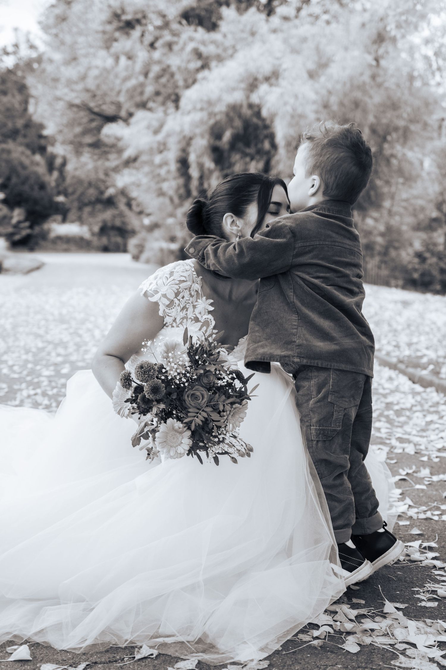 Mariés enlacés sous les arbres, bouquet à la main, photo en noir et blanc – photographe de mariage au Luxembourg