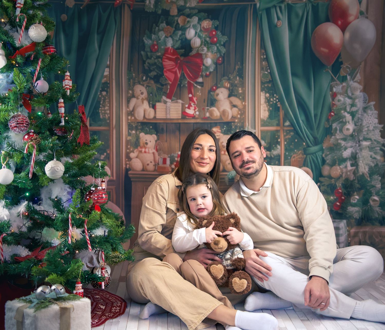 Photo lifestyle de famille en studio — parents et jeune enfant dans un décor de Noël en studio