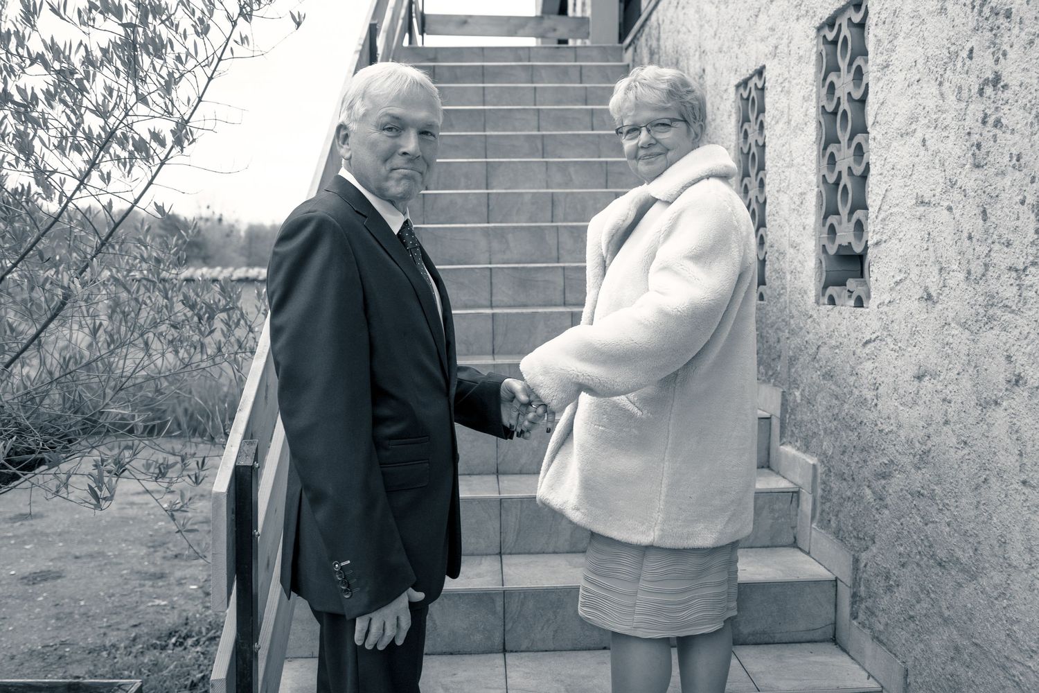 Photo en noir et blanc d'un couple de mariés se tenant la main dans un escalier — photographe mariage Lorraine