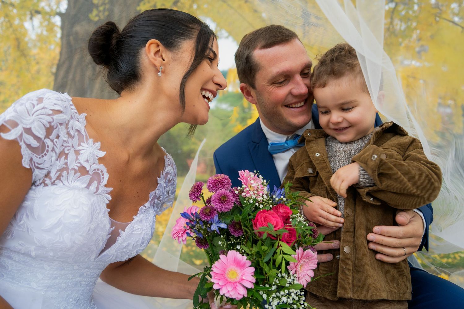 Photo des mariés avec leur enfant et le bouquet, sous le voile — photographe mariage Luxembourg
