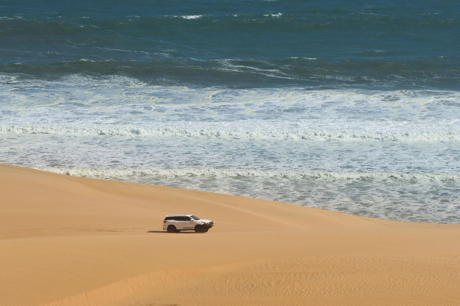 4x4 isolé entre les dunes et l'océan sur la Skeleton Coast — road trip en Namibie