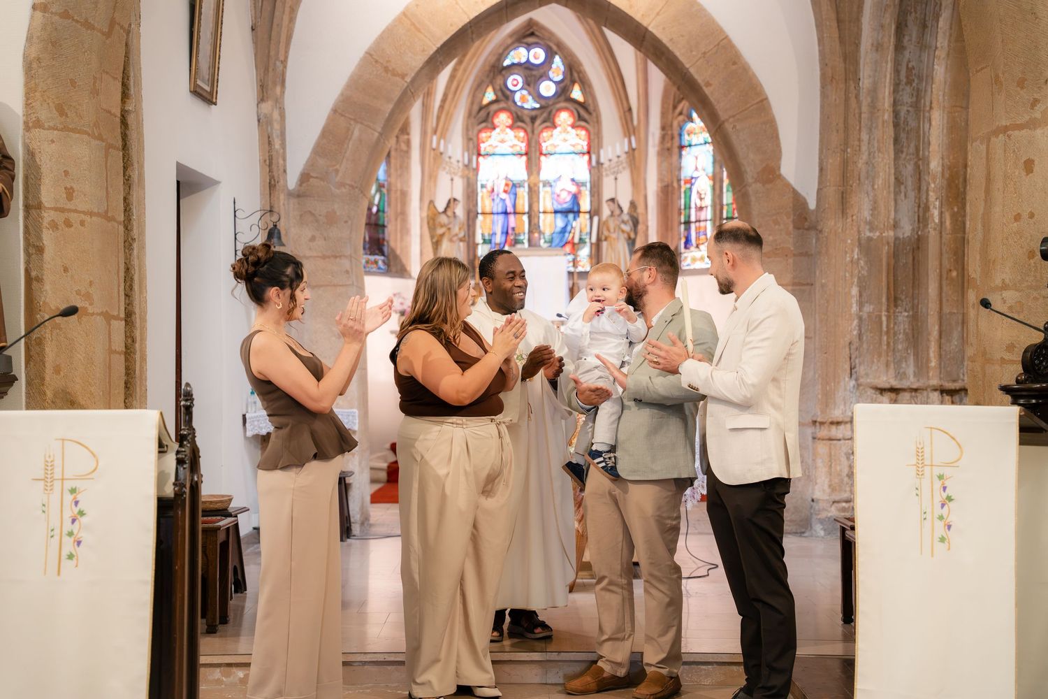 Parents et proches réunis sous les arches de pierre de l'église — photographe baptême Luxembourg