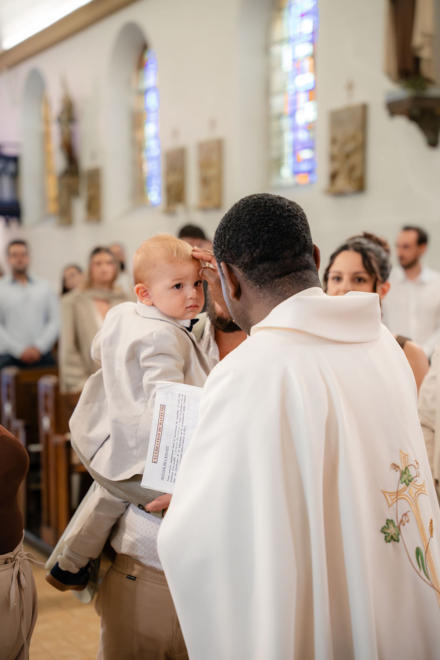L'enfant dans les bras du prêtre pendant l'onction — photographe baptême Lorraine