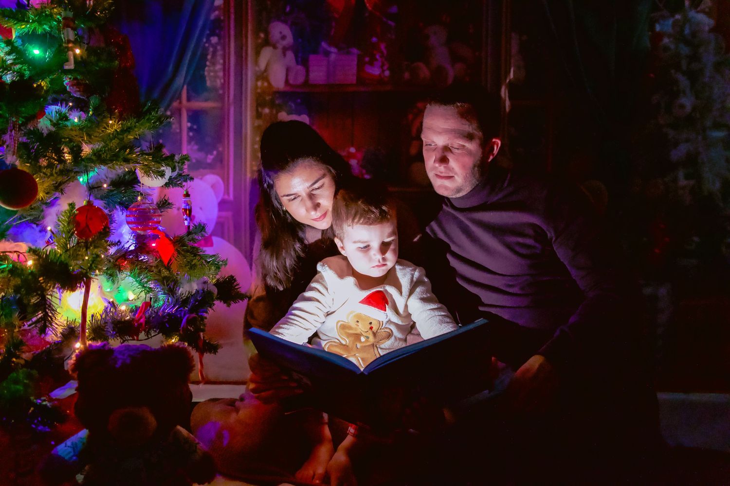 Photo lifestyle de famille en studio — parents et jeune enfant dans un décor de Noël en studio