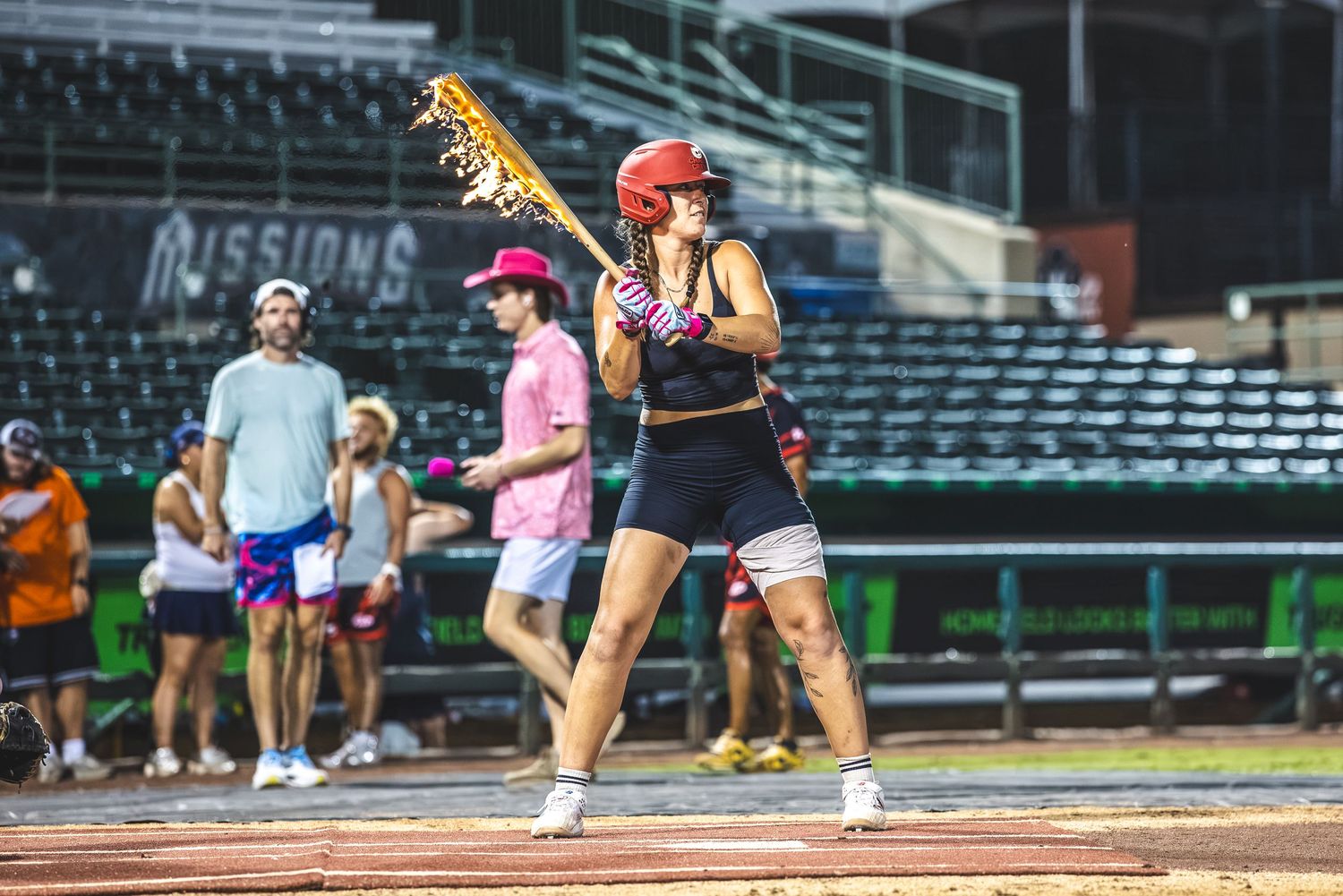 Female lacrosse player in helmet prepares to swing stick at an outdoor stadium event.