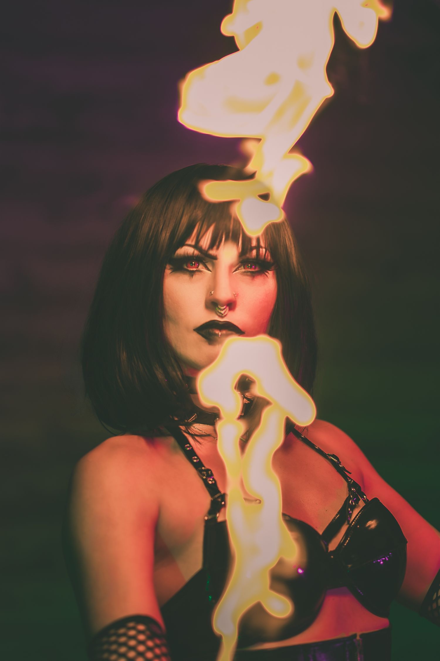 Woman performing fire breathing act with flames rising in a dark dramatic setting.
