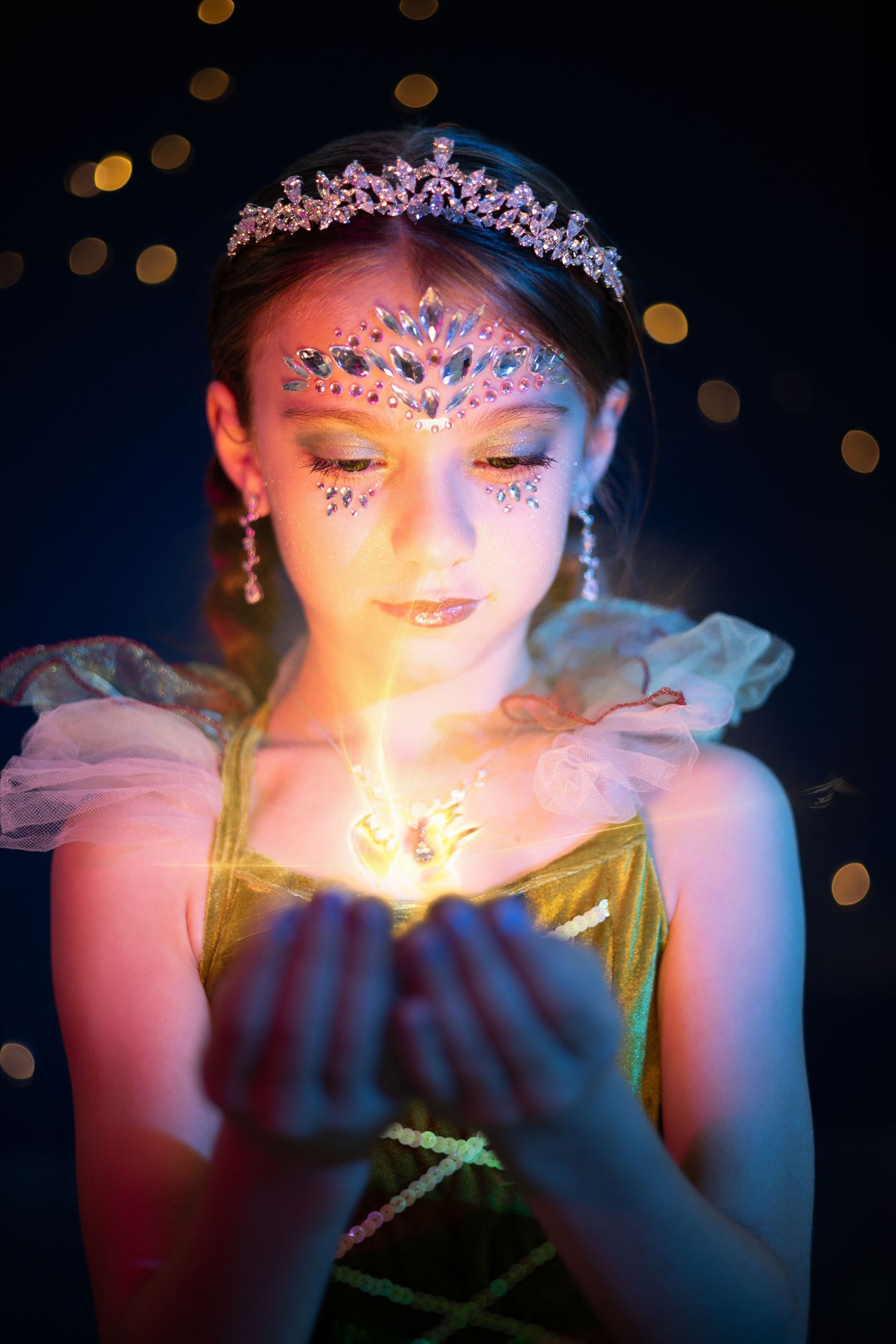 Young girl in princess costume holds glowing light in hands with bokeh background.