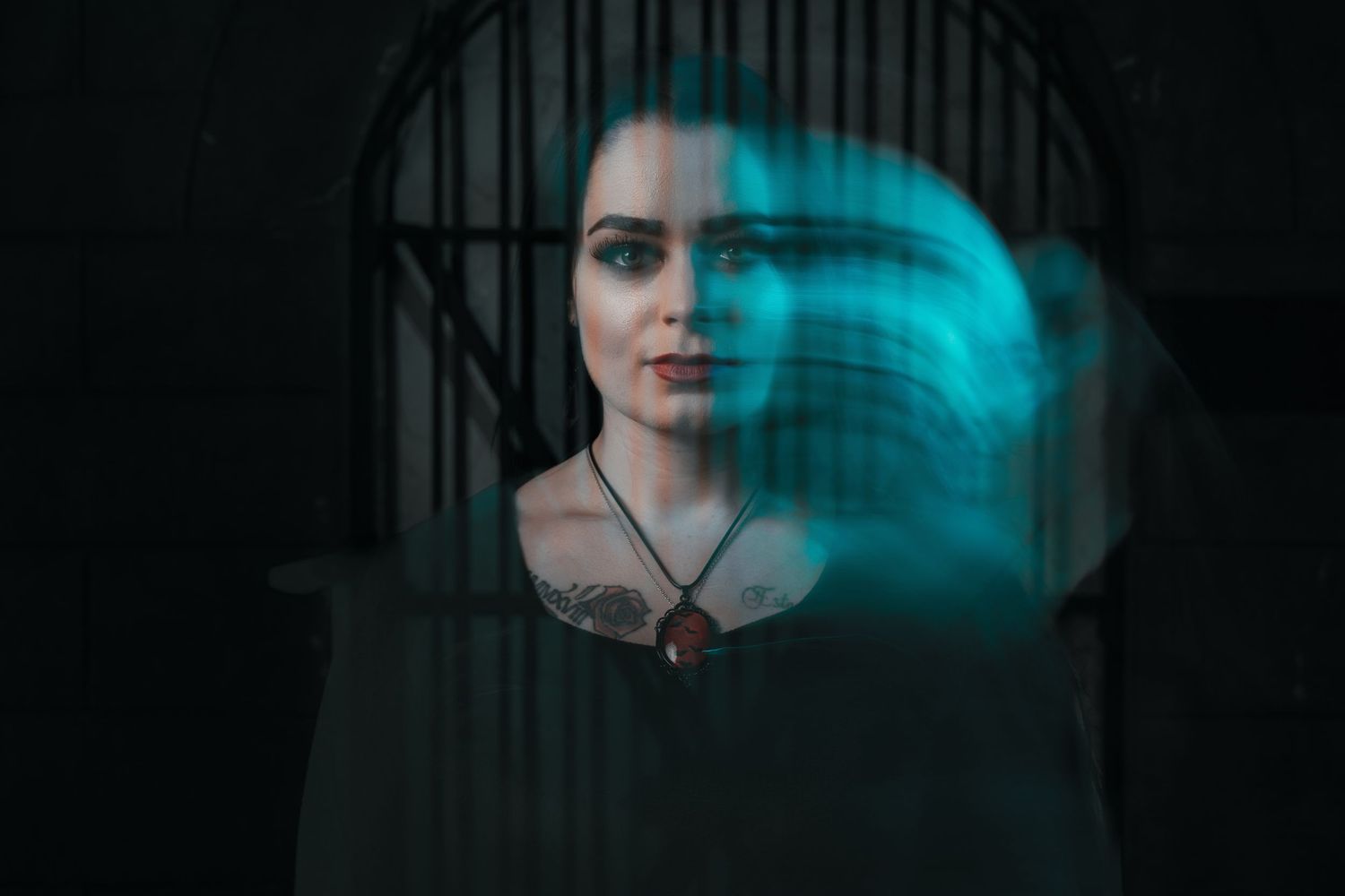 Double exposure portrait of a woman with a teal light swirl effect in dark setting.