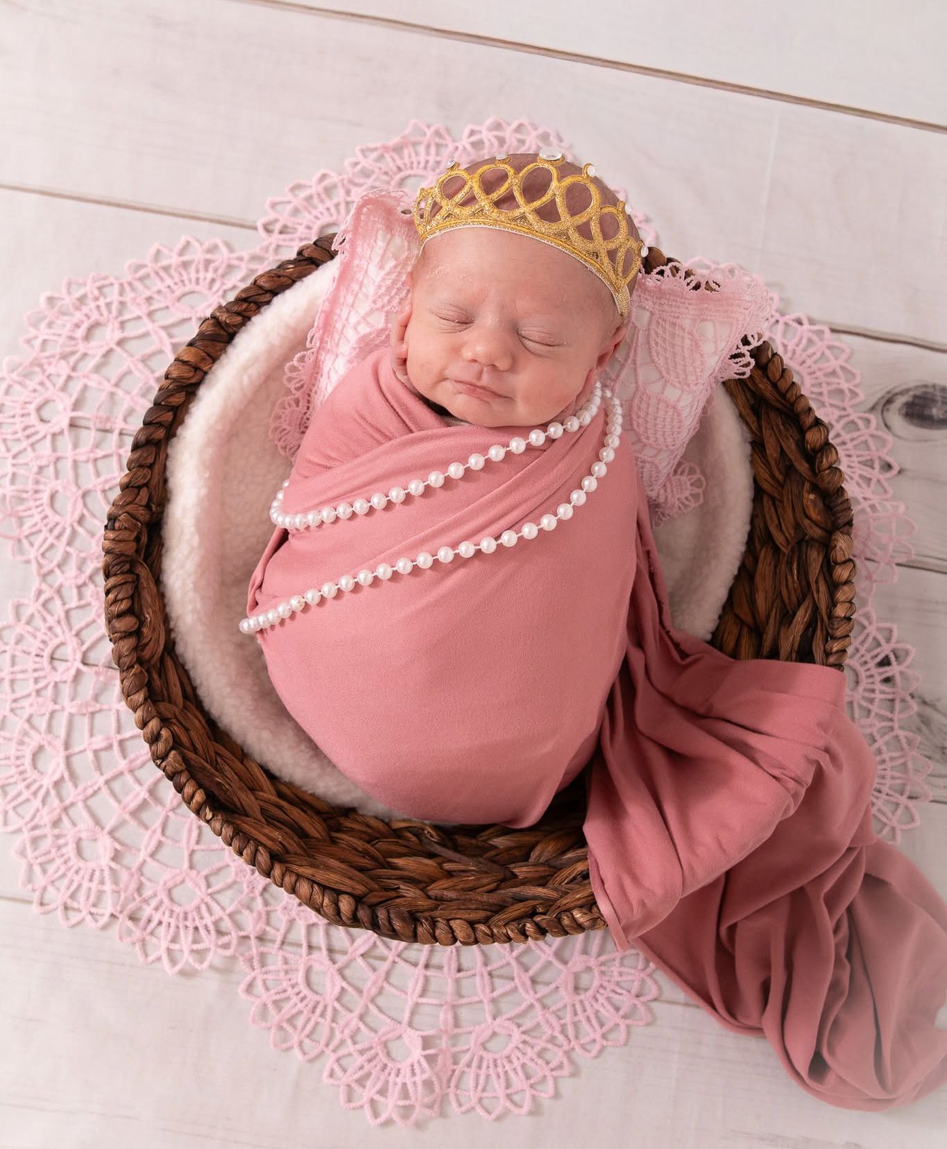 Newborn baby wrapped in soft pink with a floral headband in Springtown, TX