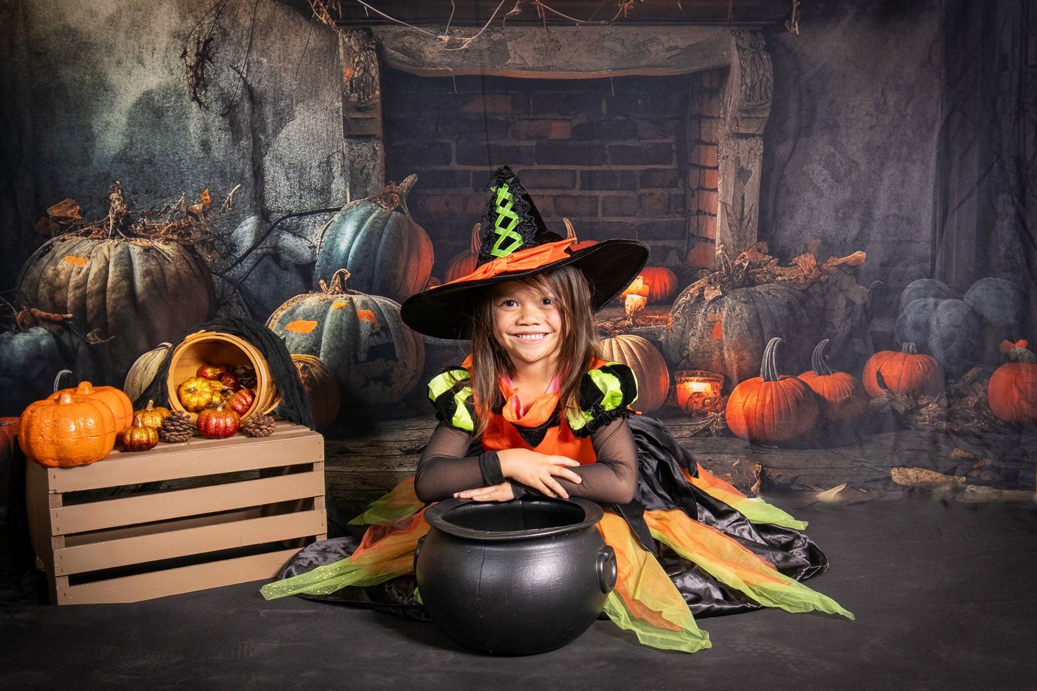 Young girl wearing a cute witch costume sitting among pumpkins and autumn decor by Tiny Toes to Tassels Photography in Springtown, TX