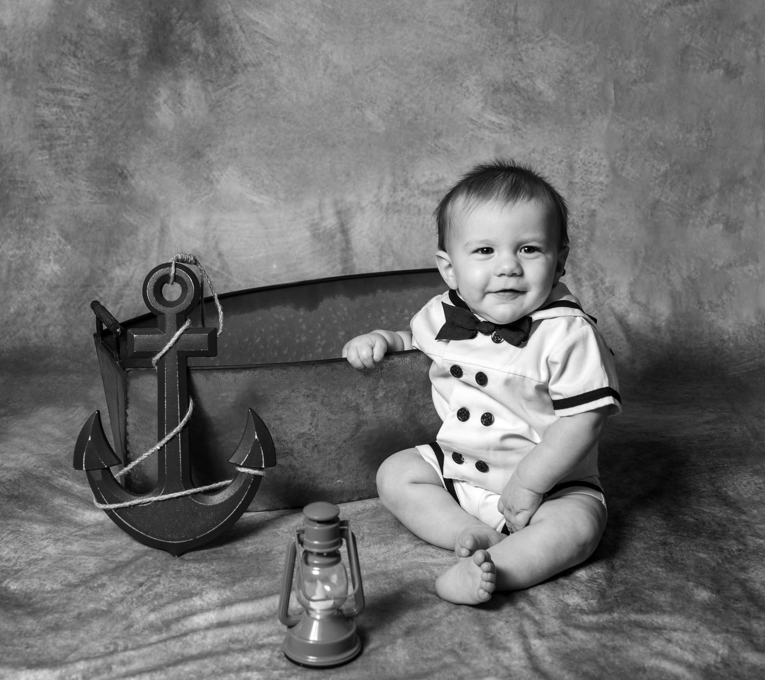 Baby boy wearing a little sailor outfit sitting with anchor and lantern props in Springtown, TX
