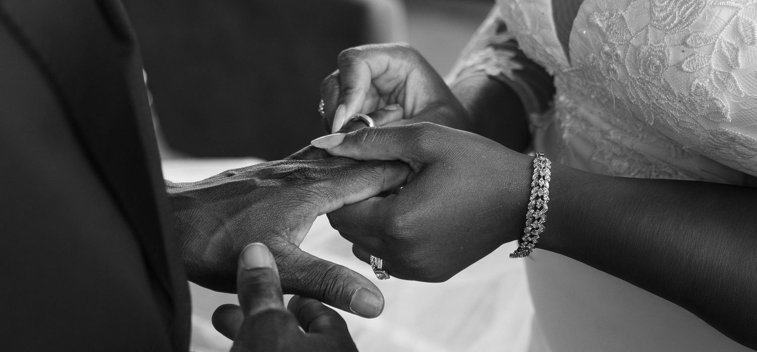 Close-up of the bride placing a wedding ring on the groom’s finger during their ceremony