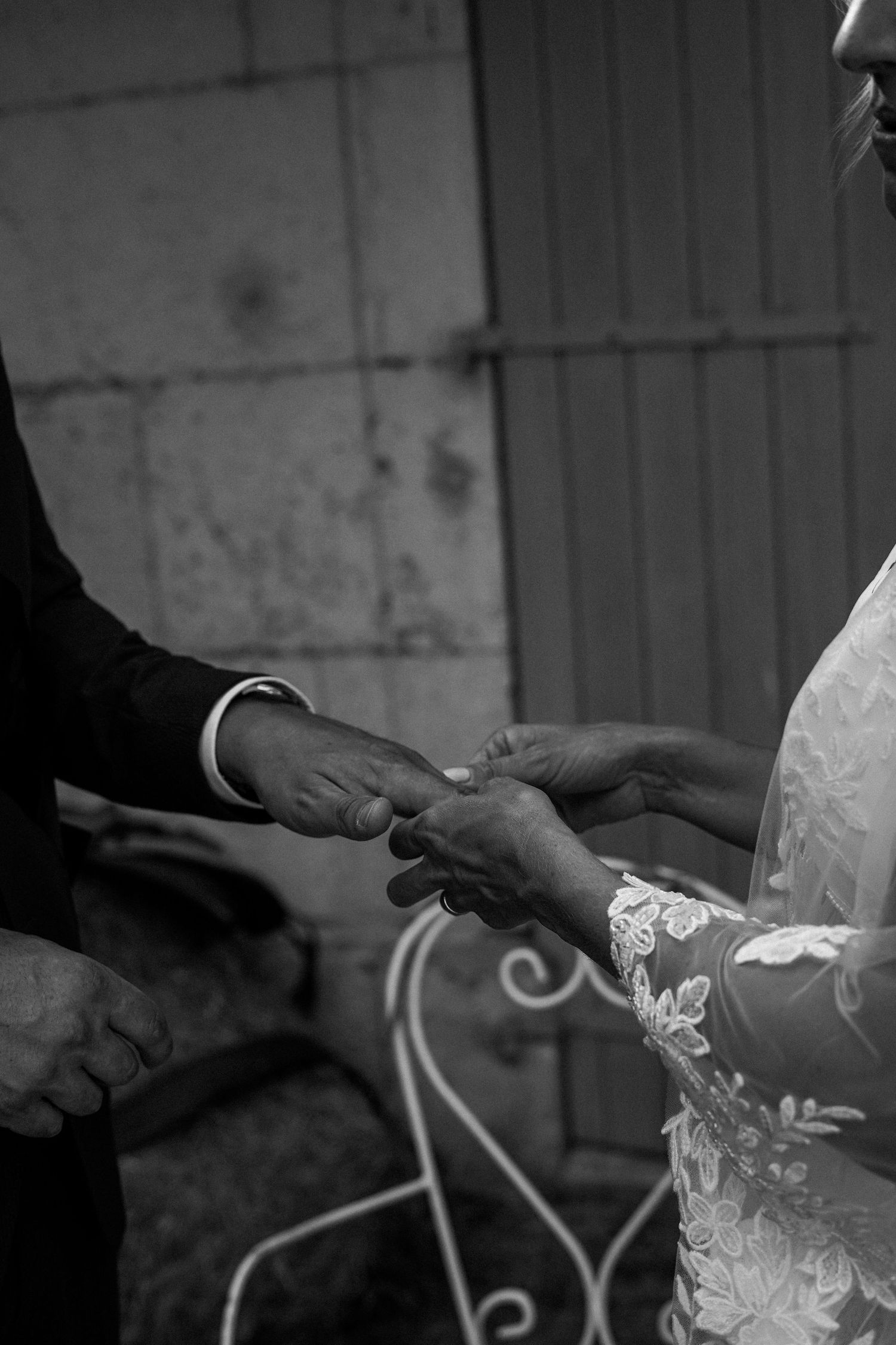 Black and white photo of bride and groom exchanging rings during wedding ceremony.