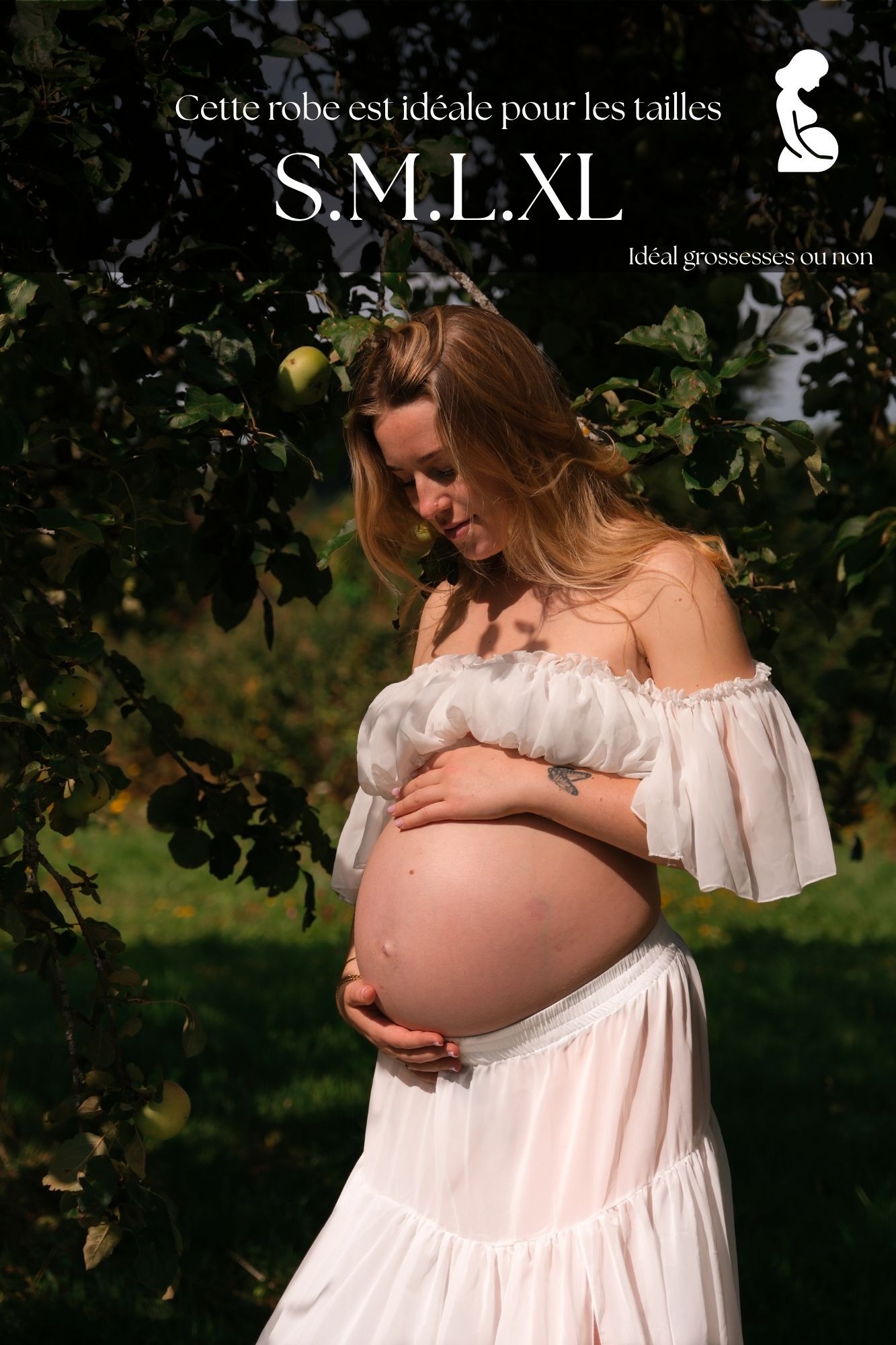 Pregnant woman in white off-shoulder dress holding baby bump outdoors near apple tree, ideal for sizes S, M, L, XL.