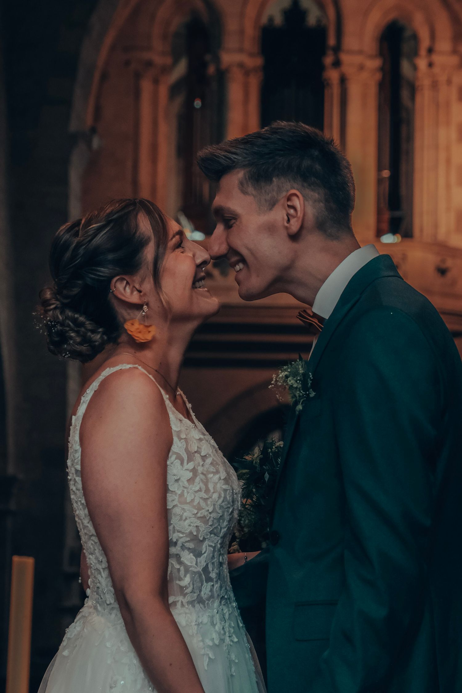 Smiling bride and groom share an intimate moment together inside a beautifully ornate church.