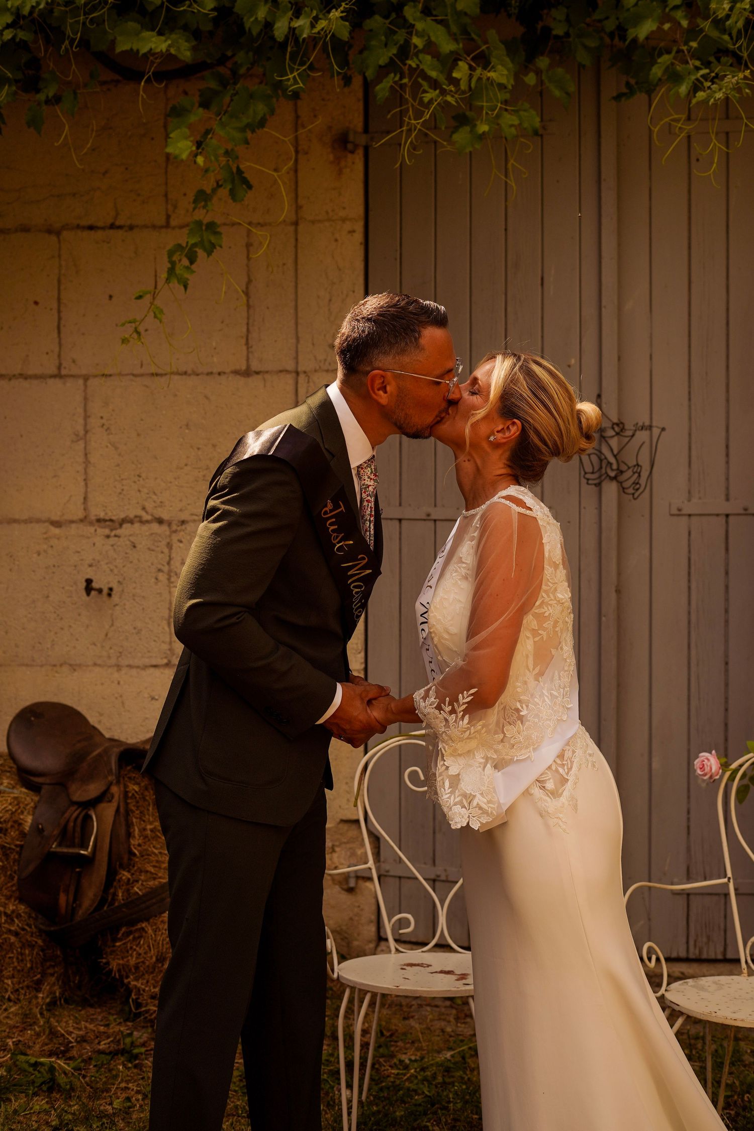 Bride and groom share a passionate kiss outdoors in rustic garden wedding setting.