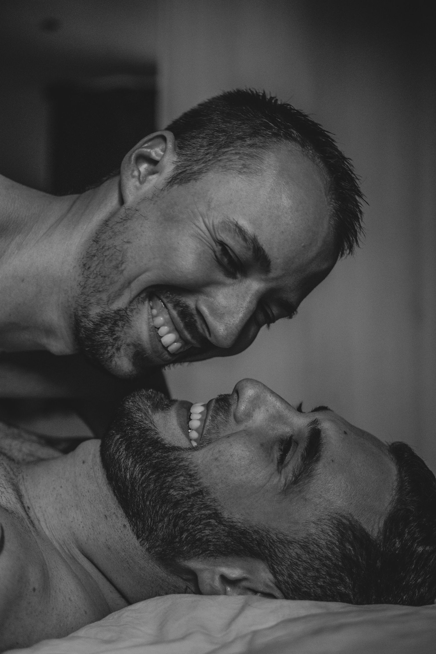 Black and white photo of two smiling men sharing a joyful intimate moment together.