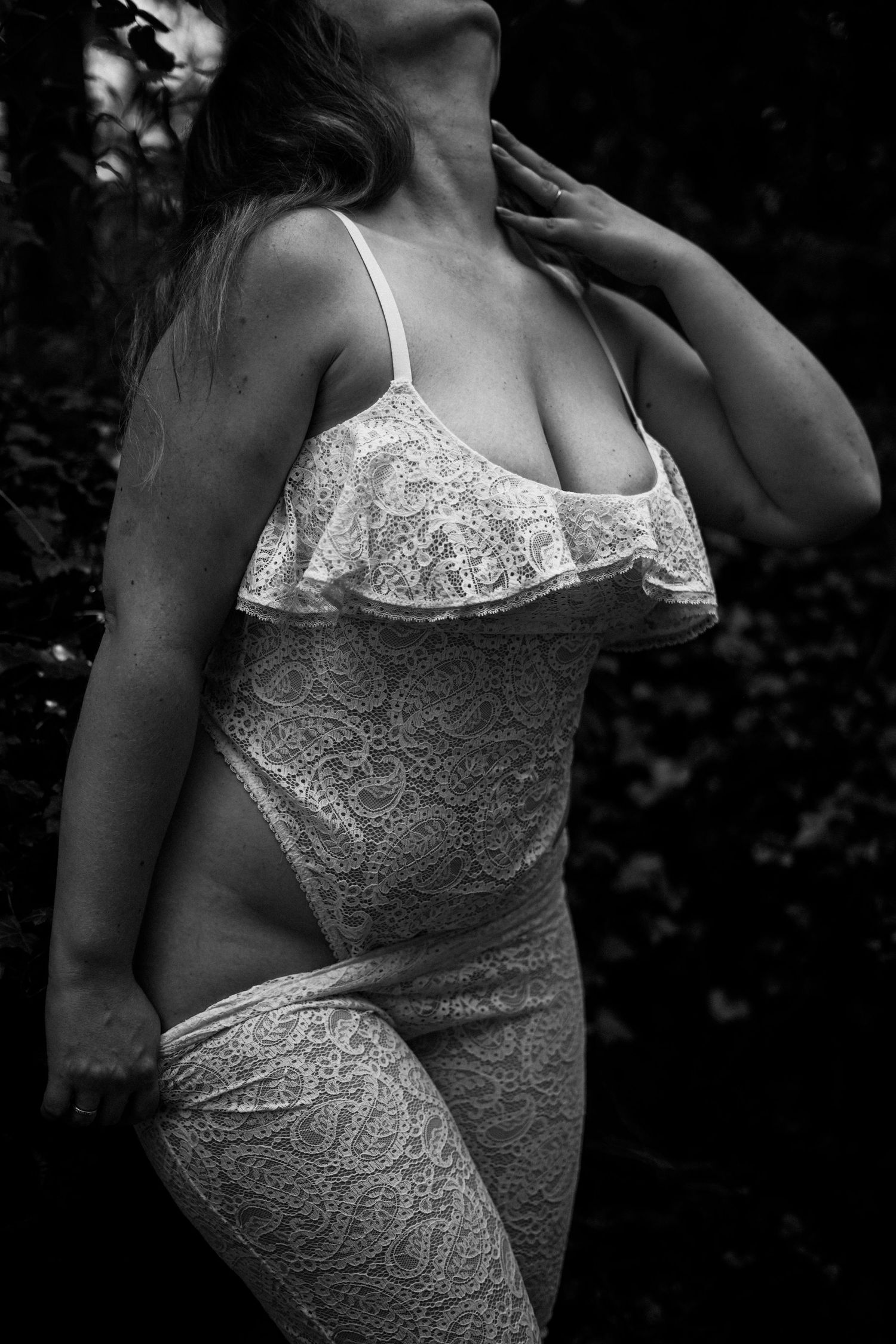 Woman in white lace dress outdoors in black and white artistic boudoir photography.