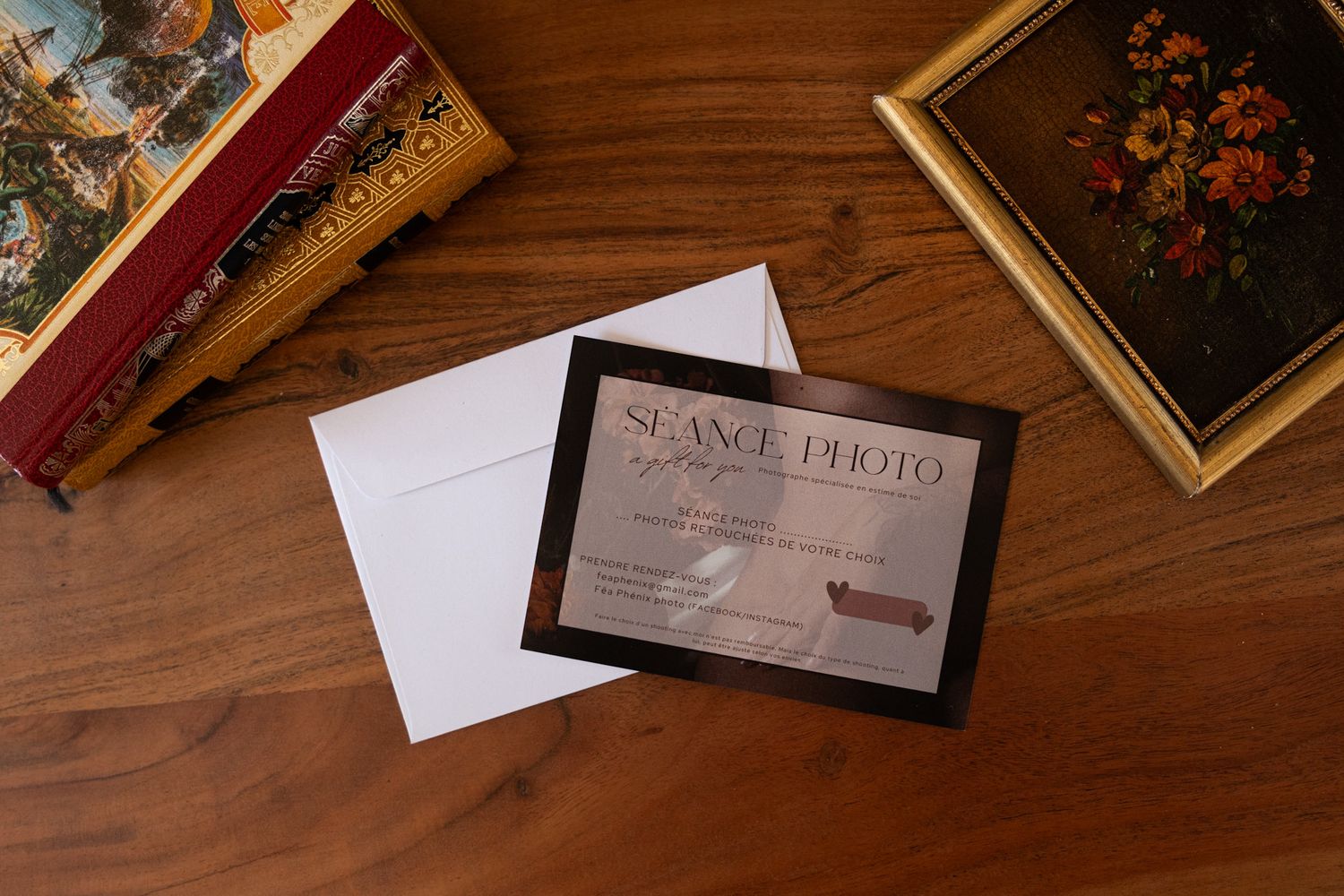 Elegant wedding photography business card and envelope displayed on a wooden table with decorative frames.