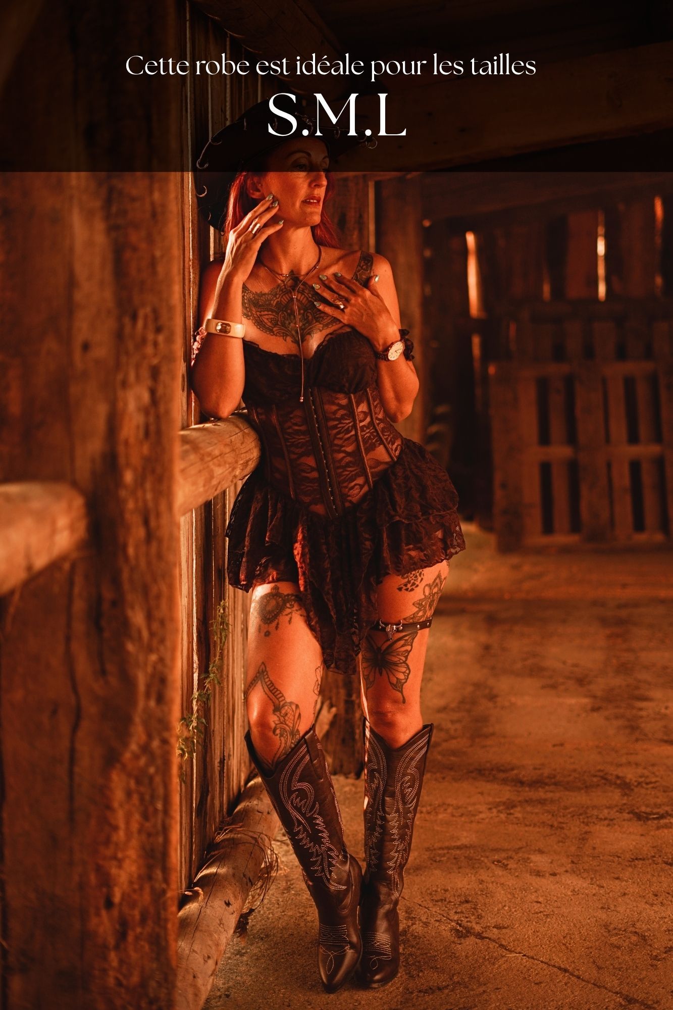 Woman in black corset dress and cowboy boots posing in rustic barn, available in sizes S, M, L.