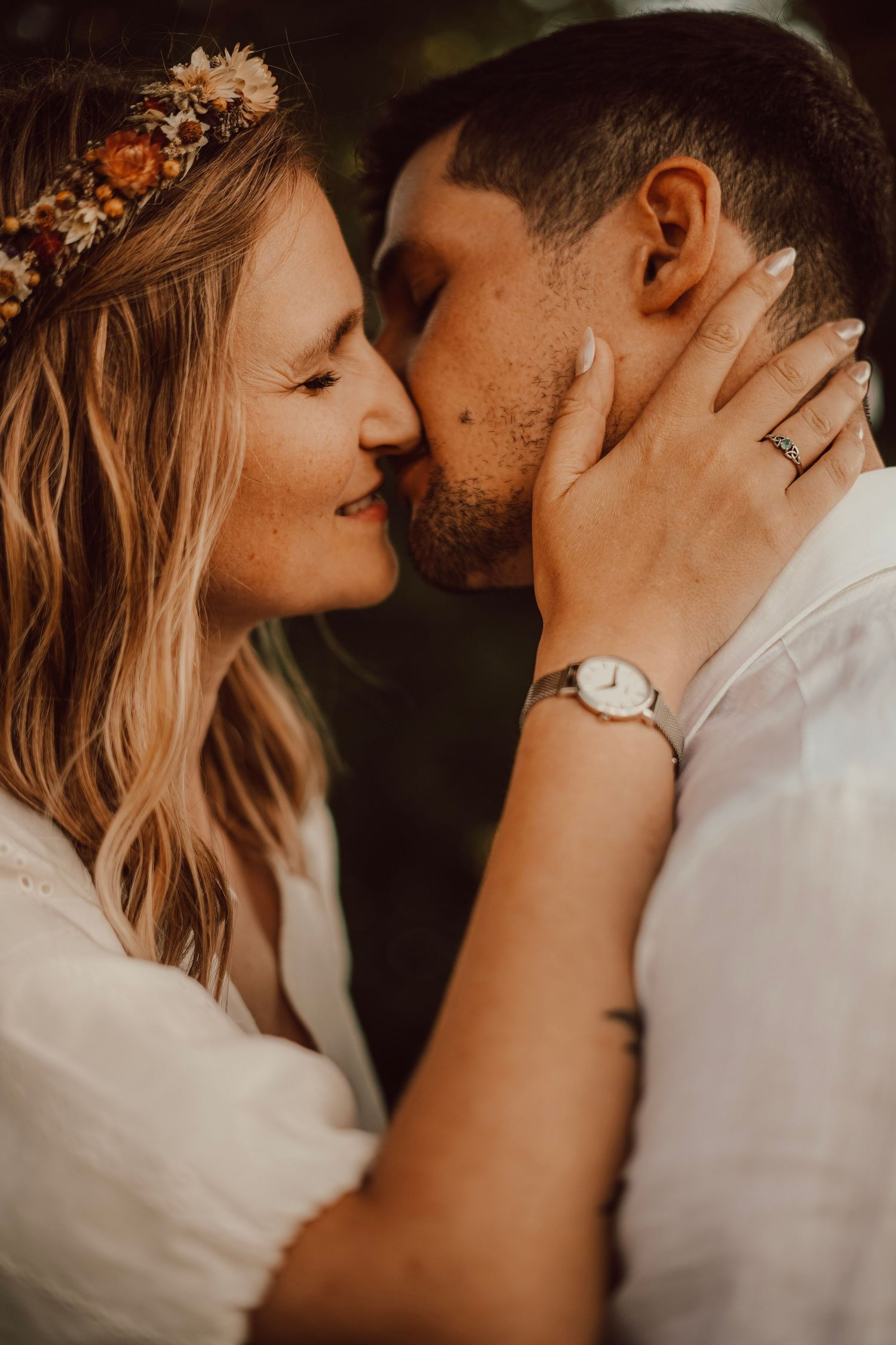 Bride with flower crown and groom sharing close romantic moment on their wedding day.