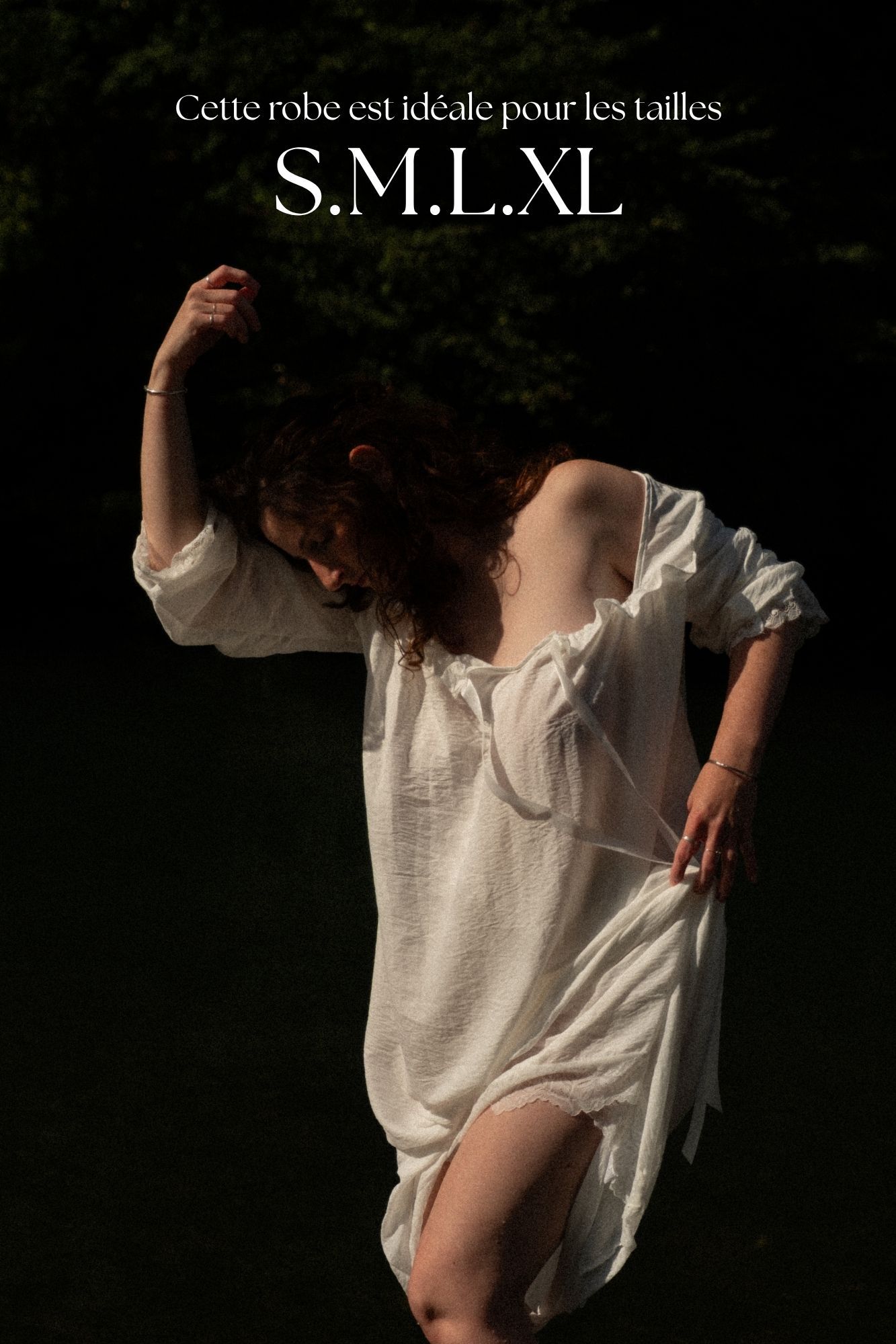 Woman in white linen oversized dress, available in sizes S, M, L, XL, posing outdoors in natural light.