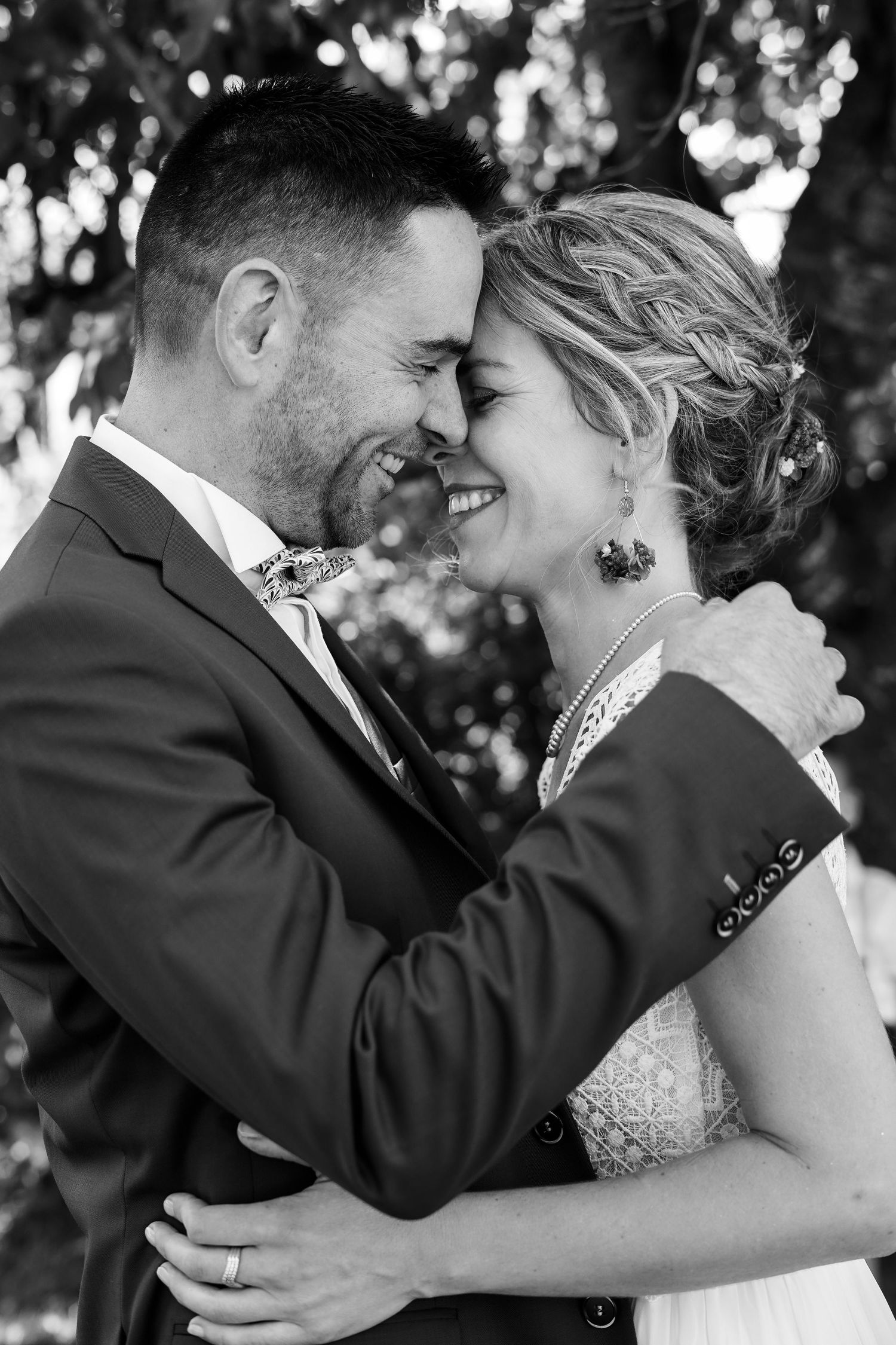 Black and white portrait of bride and groom sharing joyful embrace on wedding day.