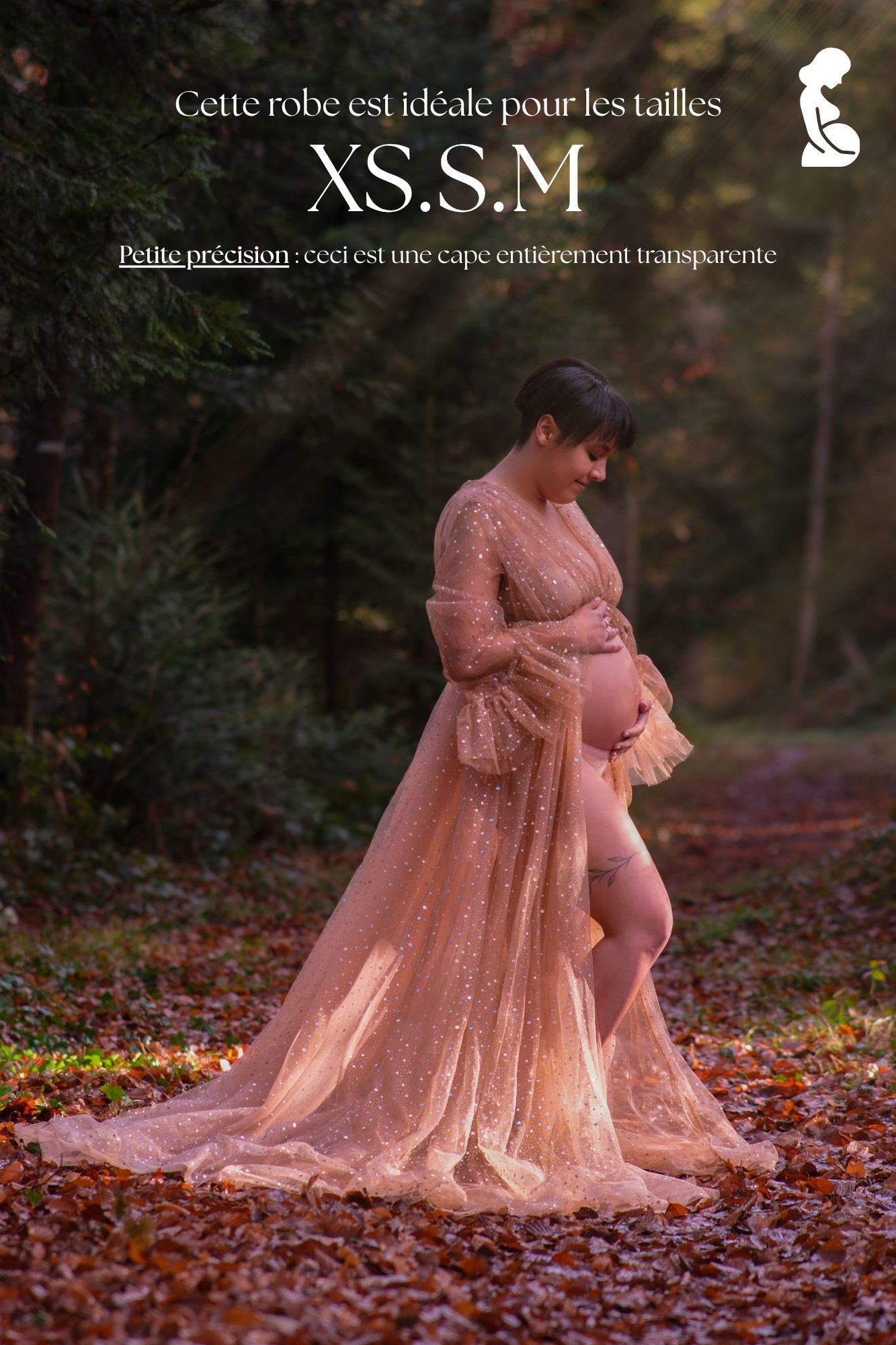 Pregnant woman in sheer sparkly rose gold maternity gown posing outdoors in autumn forest setting.
