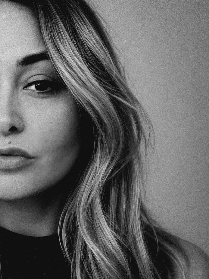 Black and white close-up portrait of young woman with long blonde hair and subtle expression.