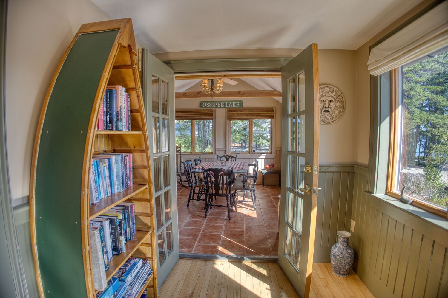 Cozy interior hallway with warm wood paneling, built-in bookshelves and large windows providing natural light.