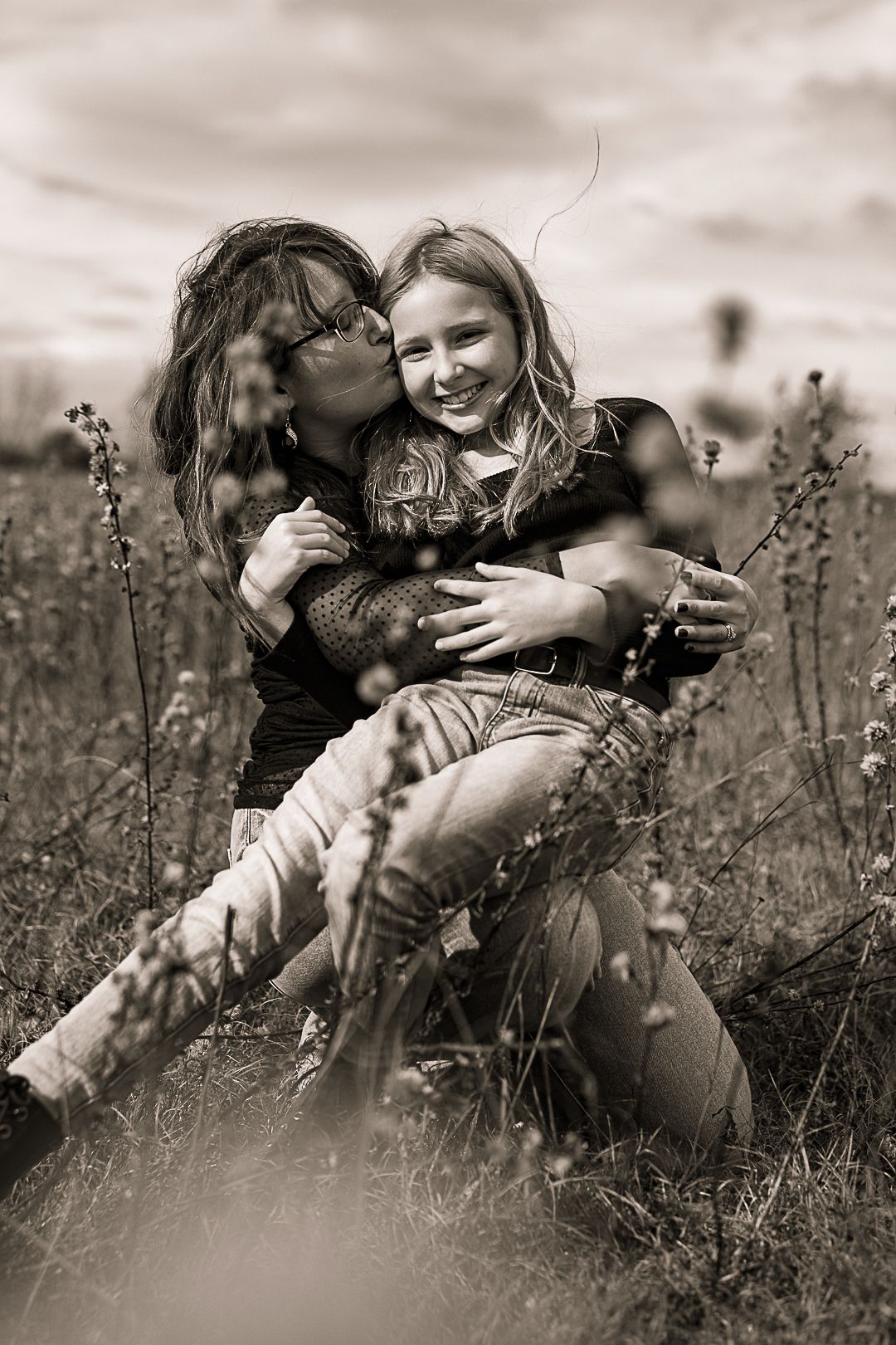 Black and white portrait of a tender moment between two people embracing in a wildflower field.