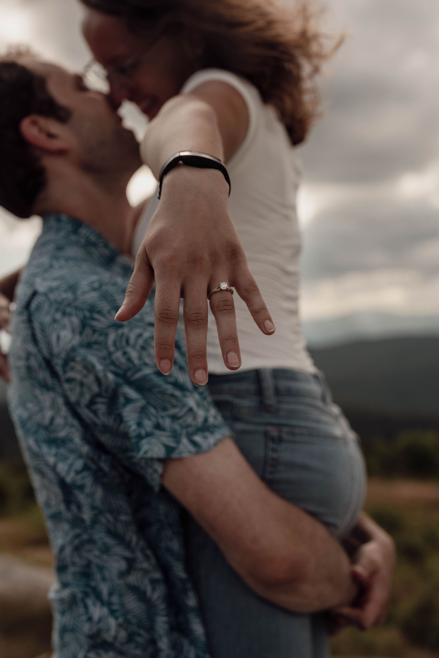 A series of close-up shots showing a romantic engagement moment with hands and a ring against a cloudy sky backdrop.